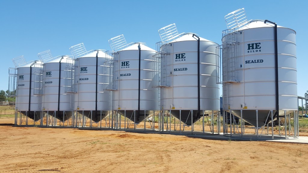 Row of large industrial helium tanks lined up outdoors under a clear blue sky.